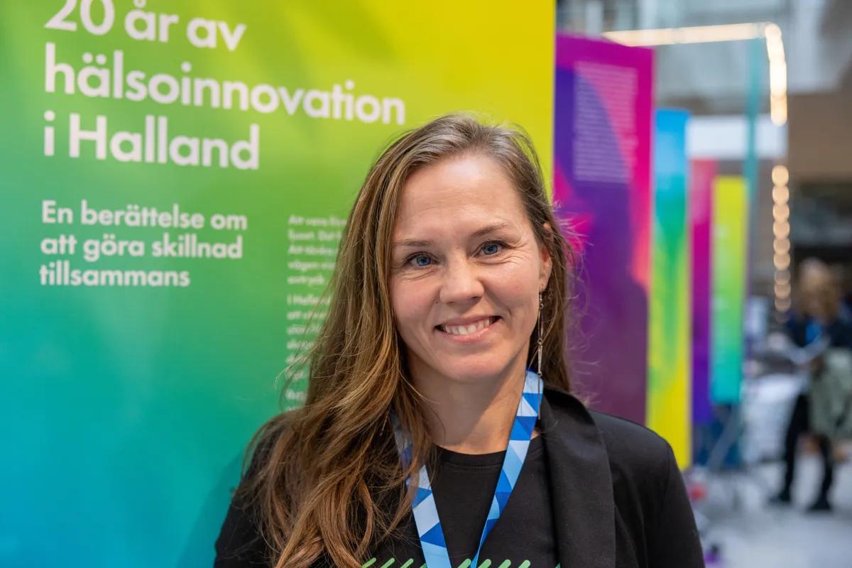 Ung kvinna står framför en färgglad mässkylt