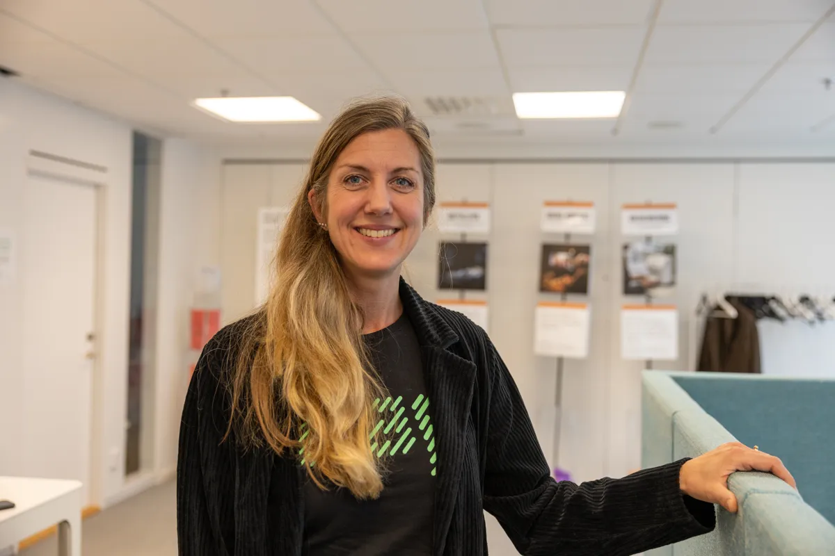 Kvinna står vid ett skrivbord och lutar sig mot en skärm