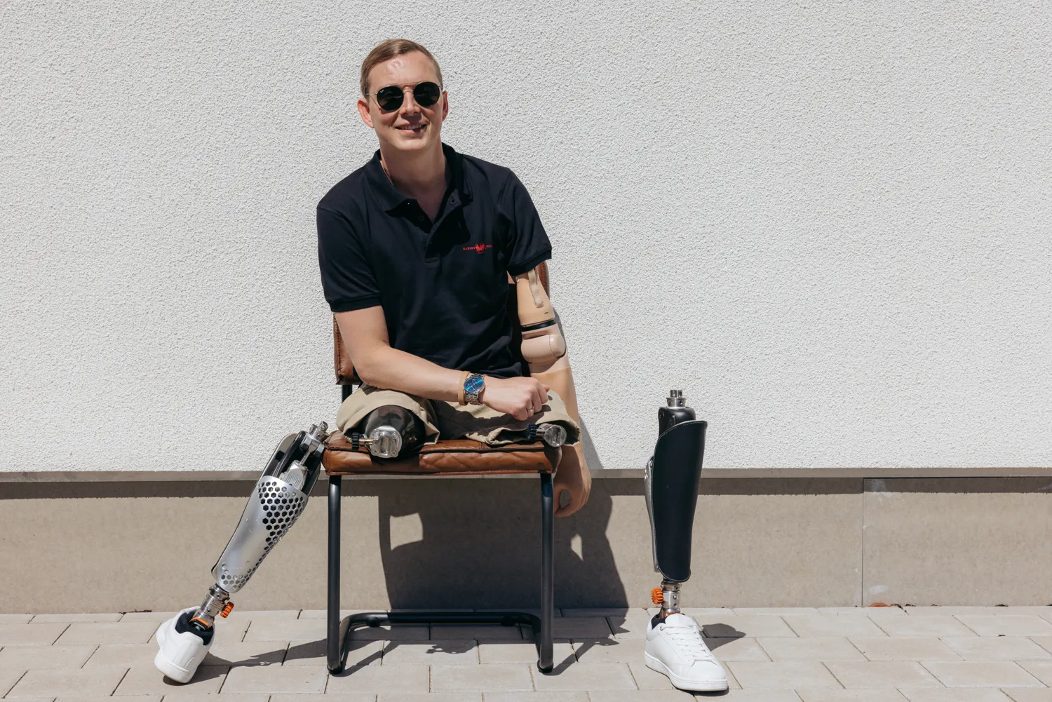 En man sitter på en stol och har sina protesfötter vid sidan av 
