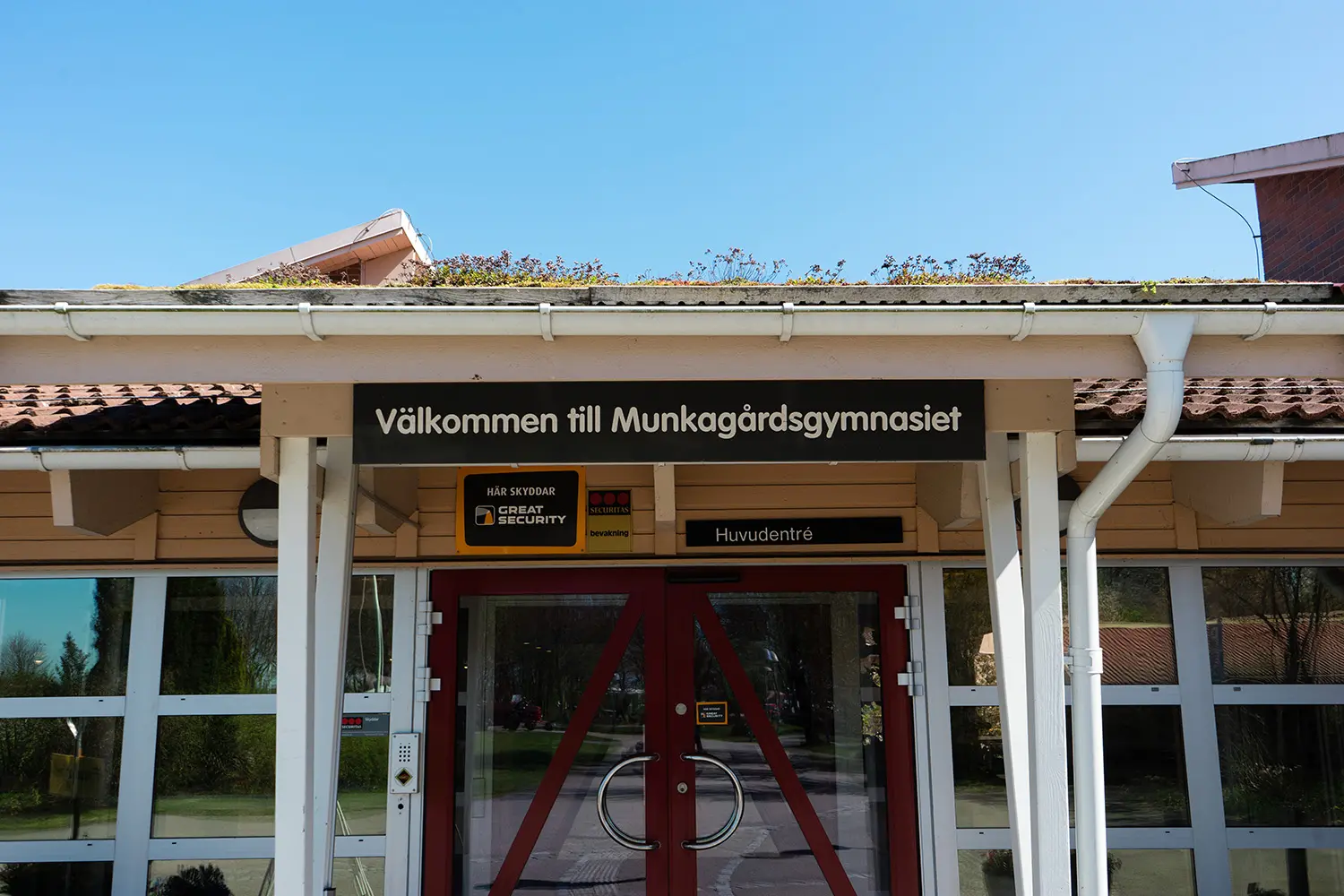 En entrédörr med en skylt ovanför, där det står "Välkommen till Munkagårdsgymnasiet".