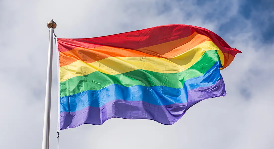 En prideflagga vajar på en flaggstång.