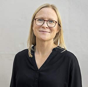 Leende kvinna med glasögon, ljust hår och svart tröja