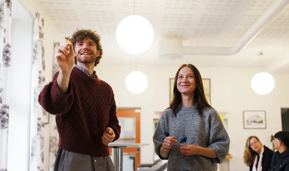 Två unga personer står och spelar dart.