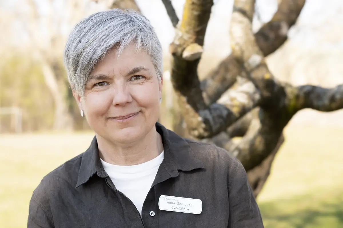 Kvinna med kort grått hår iförd en skjorta, på skjortbröstet sitter en namnskylt där det står Anna Santesson, överläkare.