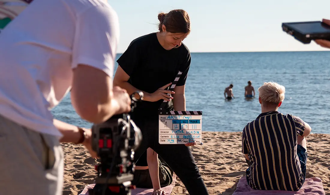 Några personer filmar på en strand.