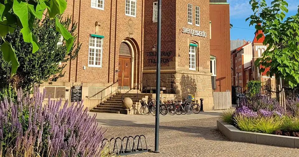 Brun tegelbyggnad med ett torg framför sig.