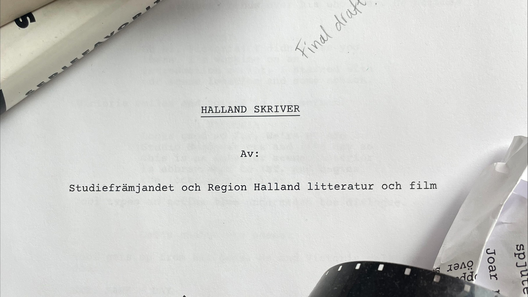 Ett maskinskrivet ark med texten "Halland skriver", ett par böcker, hopknycklat papper och en filmremsa.