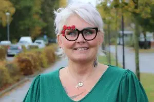 Leende ljushårig kvinna med glasögon iförd grön blus.