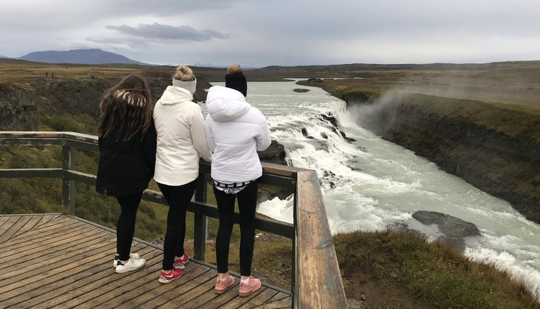 Tre personer står och tittar på ett vattenfall