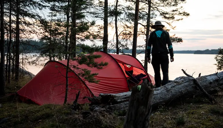 en man står bredvid ett rött tält