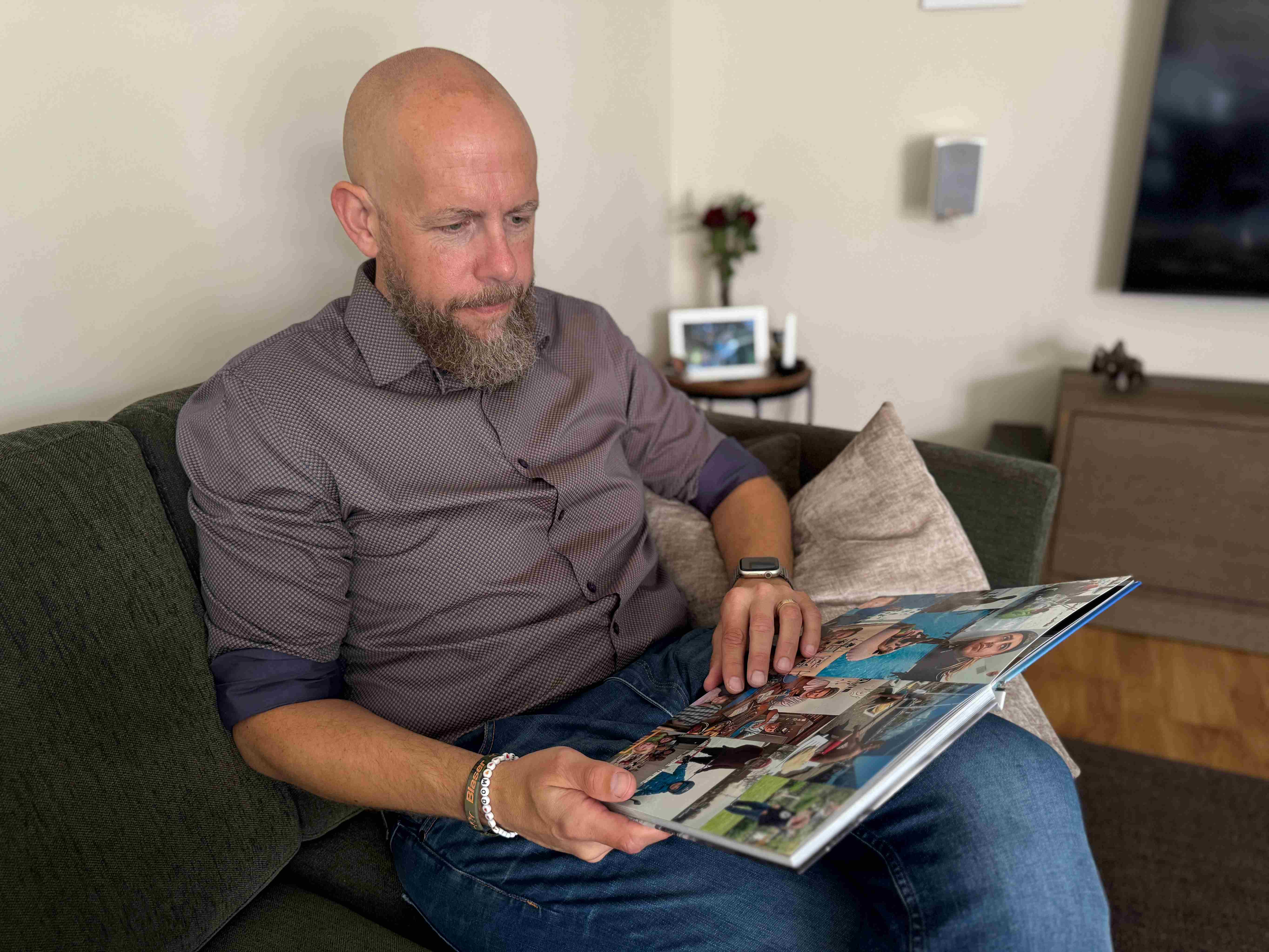 Man sitter i en soffa och bläddrar i en bok.
