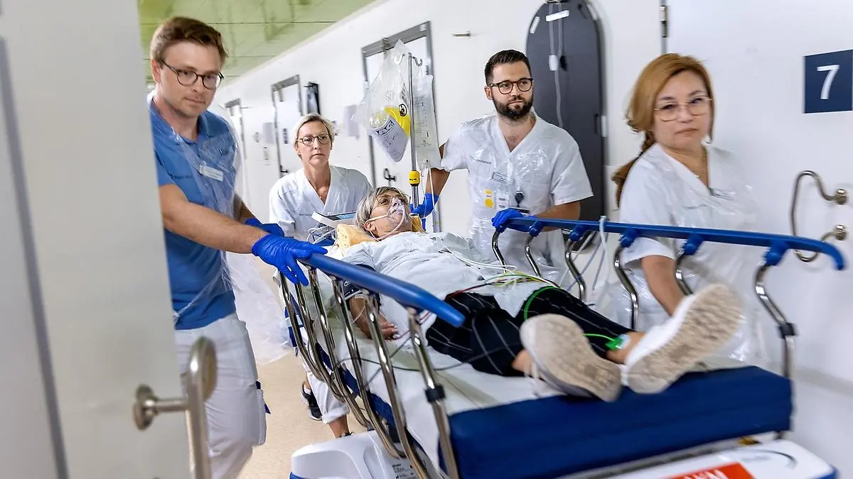 Vårdpersonal runt en person som rullas på en bår.