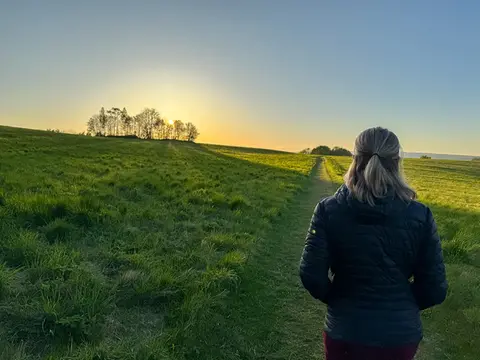 En kvinna går längs en stig på ett fält.