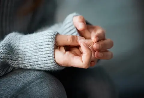 En person sitter och pillar på sina naglar.