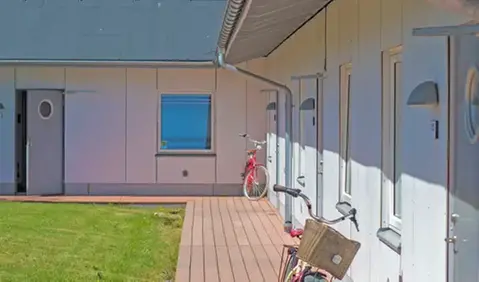 En vit enplansbyggnad med cyklar lutade mot fasaden.