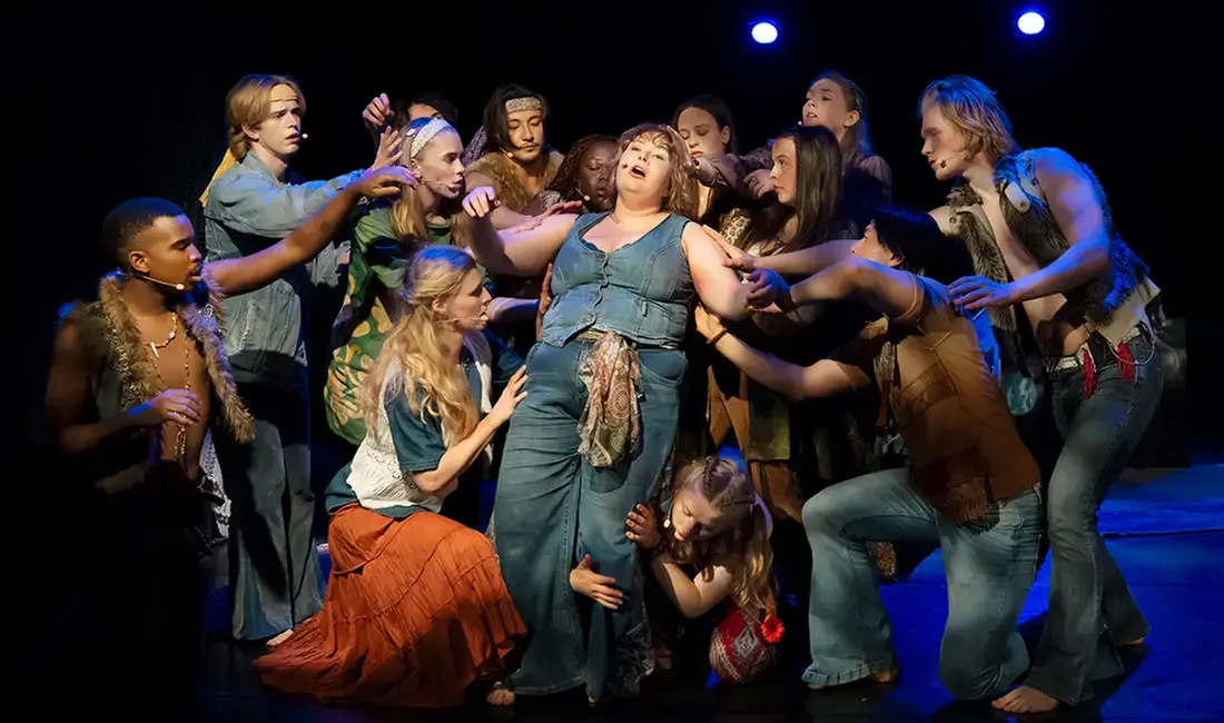 En grupp unga personer spelar en föreställning på en teaterscen.