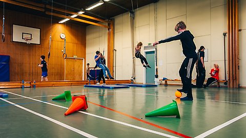 Barn som leker med olika saker i en gymnastiksal.