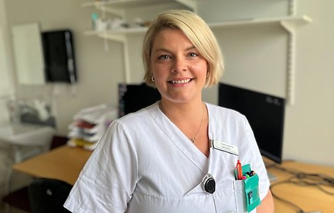 Jennifer i sjukvårdskläder tittar in i kameran och ler.